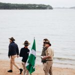 four men standing on shore near body of water